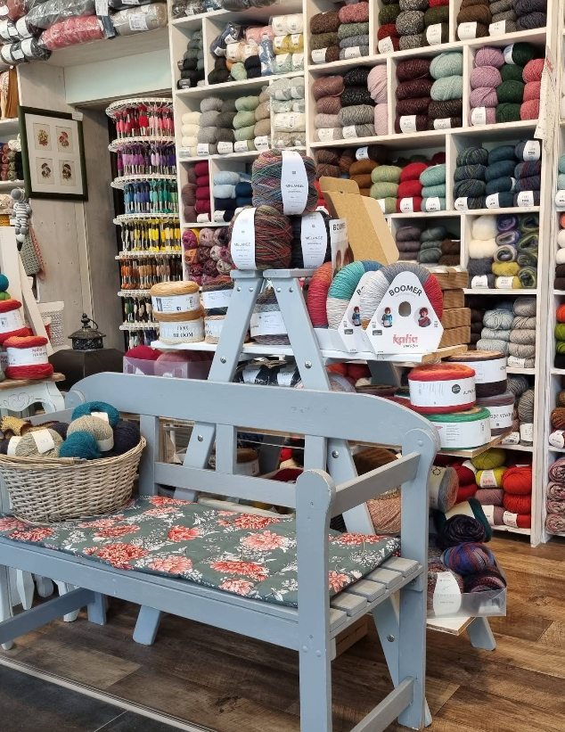 Wollecke im Laden Wollregal und Holzbank mit Kissen im Laden Patchwork Handarbeit in Annaberg-Buchholz