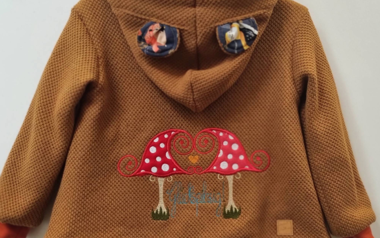 Kinderjacke mit Applikation Braune Kinderjacke mit Fliegenpilz-Applikation aus dem Handarbeitsgeschäft in Annaberg-Buchholz